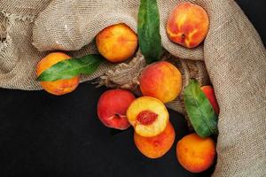 Sweet Peaches on a sharp stone table with a cloth of burlap and a slice of juicy peach with a bone. photo