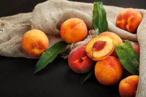 Sweet Peaches on a sharp stone table with a cloth of burlap and a slice of juicy peach with a bone. photo