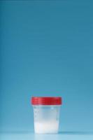 Semen in a test container with a red lid on a blue background. photo