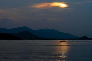 vista de la naturaleza puesta de sol de pescador de sombra en el mar y la montaña en el fondo de la isla foto