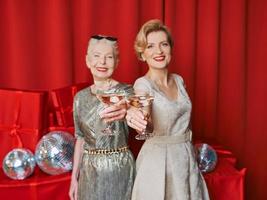 two women mature and senior celebrating New Year holding in hands glasses of white sparkling wine. Christmas, family, friends, celebrating, new year concept