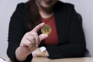 mujer de negocios sosteniendo el concepto de intercambio de criptomonedas de bitcoins. tecnología e inversión digital. financiar, comerciante, inversor, oro bitcoin efectivo, recaudar dinero foto