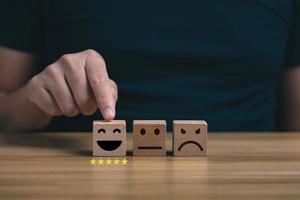 customer services best. Businessman's hand selects a smiley face on a wooden block. 5 star satisfaction, Excellent business rating experience photo