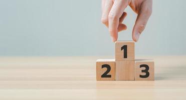 Businessman's hand chooses number 1 on the podium with number 2, 3 of wooden building blocks. ranking and strategy concept. winners podium, Business hierarchy photo