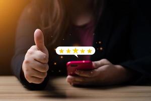 concepto de satisfacción del cliente. mano de una mujer de negocios que usa un teléfono inteligente con un ícono emergente de cinco estrellas para recibir comentarios. con espacio de copia. Satisfacción de 5 estrellas, excelente experiencia de calificación comercial foto