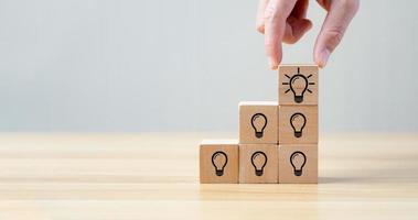 Hand of business selected wooden cube block with light bulb icon symbol and icon question mark creative concept. new ideas photo