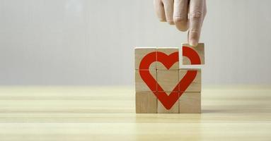 Hand hold wooden cube with heart sign icon on and copy space. Valentine love season concept. photo