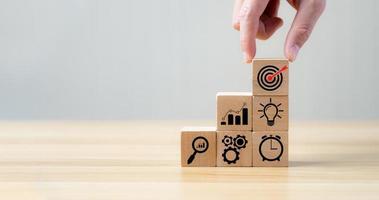 Success Concepts and Business Goals. Hand placed wooden block or selected on the table with action plan icon. Company strategy development photo