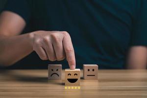 customer services best. Businessman's hand selects a smiley face on a wooden block. 5 star satisfaction, Excellent business rating experience photo