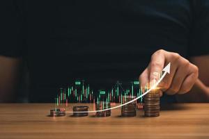 investment concept in financial business. Businessman's hands with stacks of coins showing father graph chart with arrows. Investing and profiting from trading, money growth photo