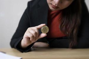 mujer de negocios en la mano monedas bitcoin con gráfico de comercio criptográfico. intercambio de criptomonedas. concepto digital de tecnología e inversión. financiar, comerciante, inversionista, oro bitcoin efectivo foto