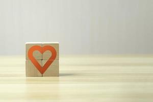 sostenga a mano un cubo de madera con un icono de signo de corazón y copie el espacio. concepto de temporada de amor de san valentín. foto