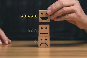 customer services best. Businessman's hand selects a smiley face on a wooden block. 5 star satisfaction, Excellent business rating experience photo