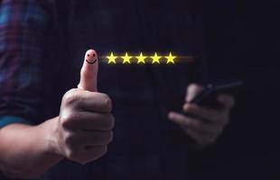 Customer satisfaction concept. Hand with thumb up Positive emotion smiley face icon and five star with copy space. 5 star satisfaction, Excellent business rating experience photo