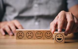 Users choose the highest satisfaction. Businessman's hand selects a smiley face on a wooden block. 5 star satisfaction. Excellent business rating experience. Satisfaction survey concept. photo