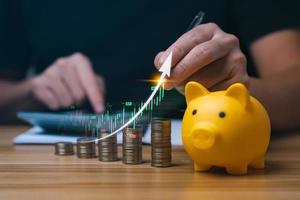 businessman analyzing forex trading graph financial data. coin in a piggy bank and arrows showing charts on his desk. concept of money growth and business finance, successful investment strategy photo