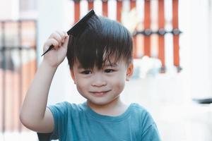 lindo chico asiático peinándose en casa, chico de corte de pelo o concepto de peluquero foto