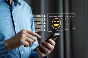 Measuring how happy customers are with a business's products or services through smartphone screen application to choose 5 star and smiley face emoji. reviews, opinions, recommendations photo