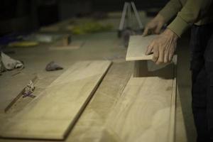 Carpenter holds tree. Worker chooses board. Details of carpentry workshop. photo