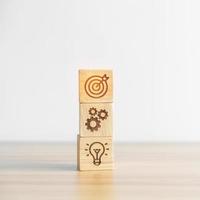 dartboard above Gear and Lightbulb icon block on desk. business planning process, goal, strategy, target, mission, action, objective, teamwork and idea concept photo