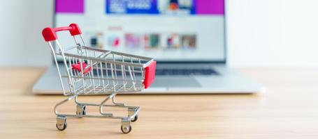 Shopping cart and laptop computer with marketplace website. business, technology, ecommerce, digital banking and online payment concept photo