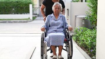 cuidador ajuda e cuida paciente idosa asiática ou idosa sentada na cadeira de rodas para rampa no hospital de enfermagem, conceito médico forte e saudável. video