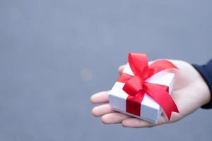 White ribbon gift box in hand for lovers on Valentine's Day photo