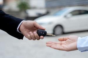 Salesman is carrying the car keys delivered to the customer at the showroom with a low interest offer. Special promotion photo