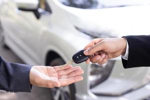 el vendedor lleva las llaves del auto entregadas al cliente en la sala de exposición con una oferta de bajo interés. promoción especial foto