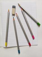 colored pencils, eraser and notebook on a white background photo