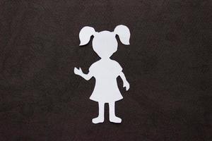 The form of a girl in a dress and with ponytails made of white paper, cut by hand. photo