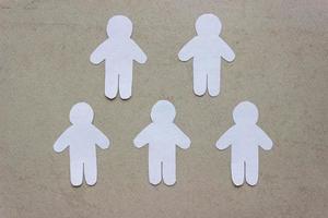 Silhouettes of five people cut from white paper. On beige background. Group of people. Teamwork, communication, togetherness, friendship photo