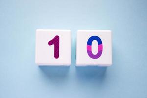 Close-up photo of a white plastic cubes with a colorful number 10 on a blue background. Object in the center of the photo