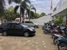 BLITAR, INDONESIA - October 20th 2022 Several cars and motorbikes are neatly parked in the yard of a local bank office photo