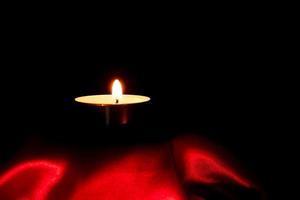 luz de velas y fondo de tela roja en la oscuridad con espacio para texto o imagen. concepto de amor de San Valentín foto