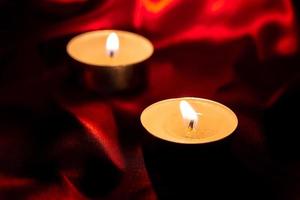 luz de velas y fondo de tela roja en la oscuridad con espacio para texto o imagen. concepto de amor de San Valentín foto