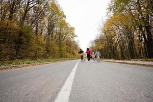 Mother with four kids running on road at autumn fall forest. photo