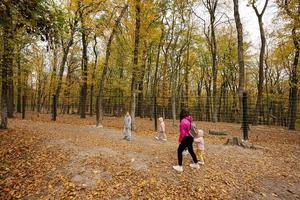 Mother with kids on a walk in autumn forest. photo