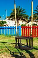 Swing in the playground with colored fences in the background. Vertical image. photo