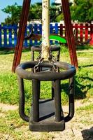 Swing in the playground with colored fences in the background. Vertical image. photo