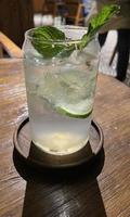 Selective focus, Delicious refreshing summer mojito with ice, lime and mint in a glass with grops. wood background photo