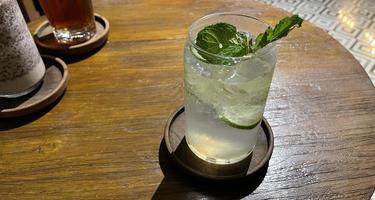 Selective focus, Delicious refreshing summer mojito with ice, lime and mint in a glass with grops. wood background photo