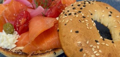 Selective focus, delicious bagel with smoked salmon, spinach, red onions, tomatoes, avocado and cream cheese photo