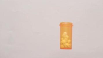 Slow motion of orange pill bottle dropping to a table with tablets falling out video