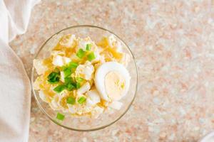 Homemade potato salad with egg and green onions in a bowl on the table. Top view. Close-up photo