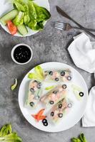 Spring rolls in rice paper made from shrimp, olives, lettuce and vegetables on a plate. Top view photo