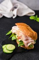 sándwich listo para comer con tocino, pepino, queso y albahaca. comida rápida casera. vista vertical foto