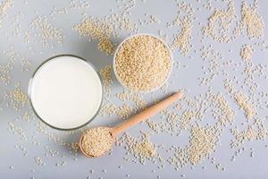 Sesame milk in a glass and seeds in a bowl on the table. Dairy Alternative. Top view photo