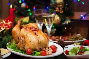 Baked turkey or chicken. The Christmas table is served with a turkey, decorated with bright tinsel and candles. Fried chicken, table. Christmas dinner. photo