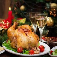 Baked turkey or chicken. The Christmas table is served with a turkey, decorated with bright tinsel and candles. Fried chicken, table. Christmas dinner. photo